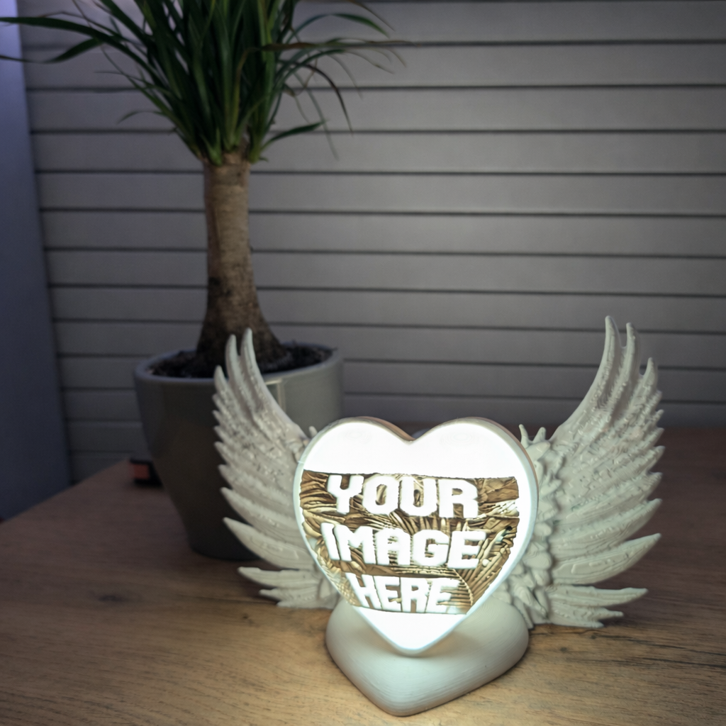 Personalised Decorative heart-shaped lamp with wings on a wooden surface, plant in the background