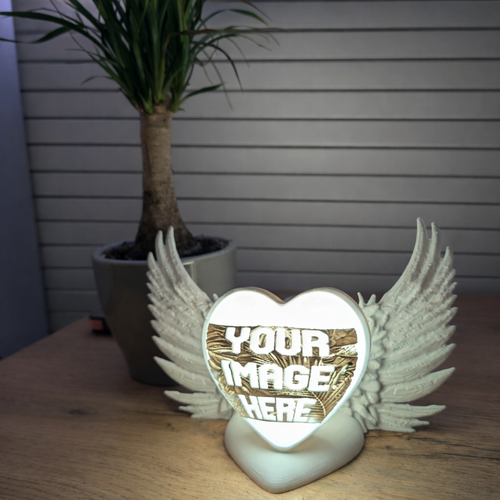 Personalised Decorative heart-shaped lamp with wings on a wooden surface, plant in the background