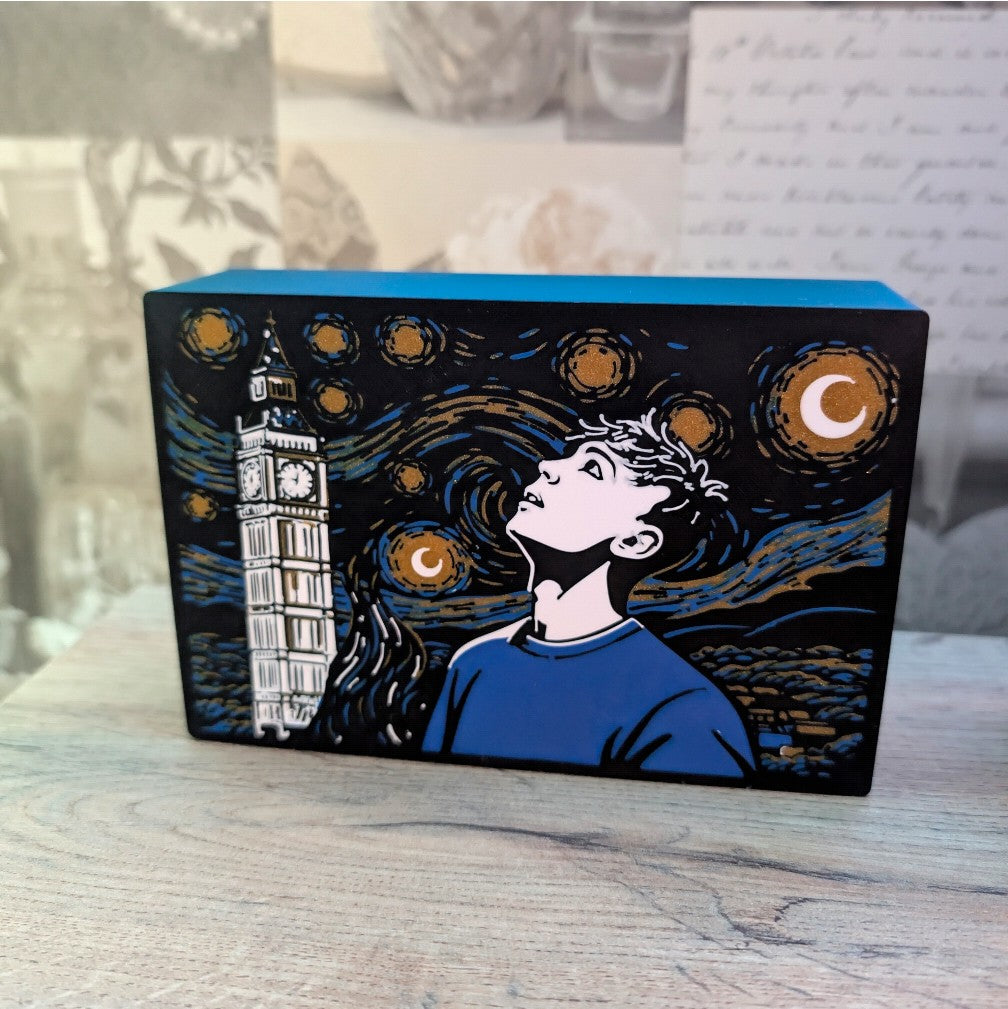 Decorative box with artistic design of a person looking at Big Ben against a starry night sky.